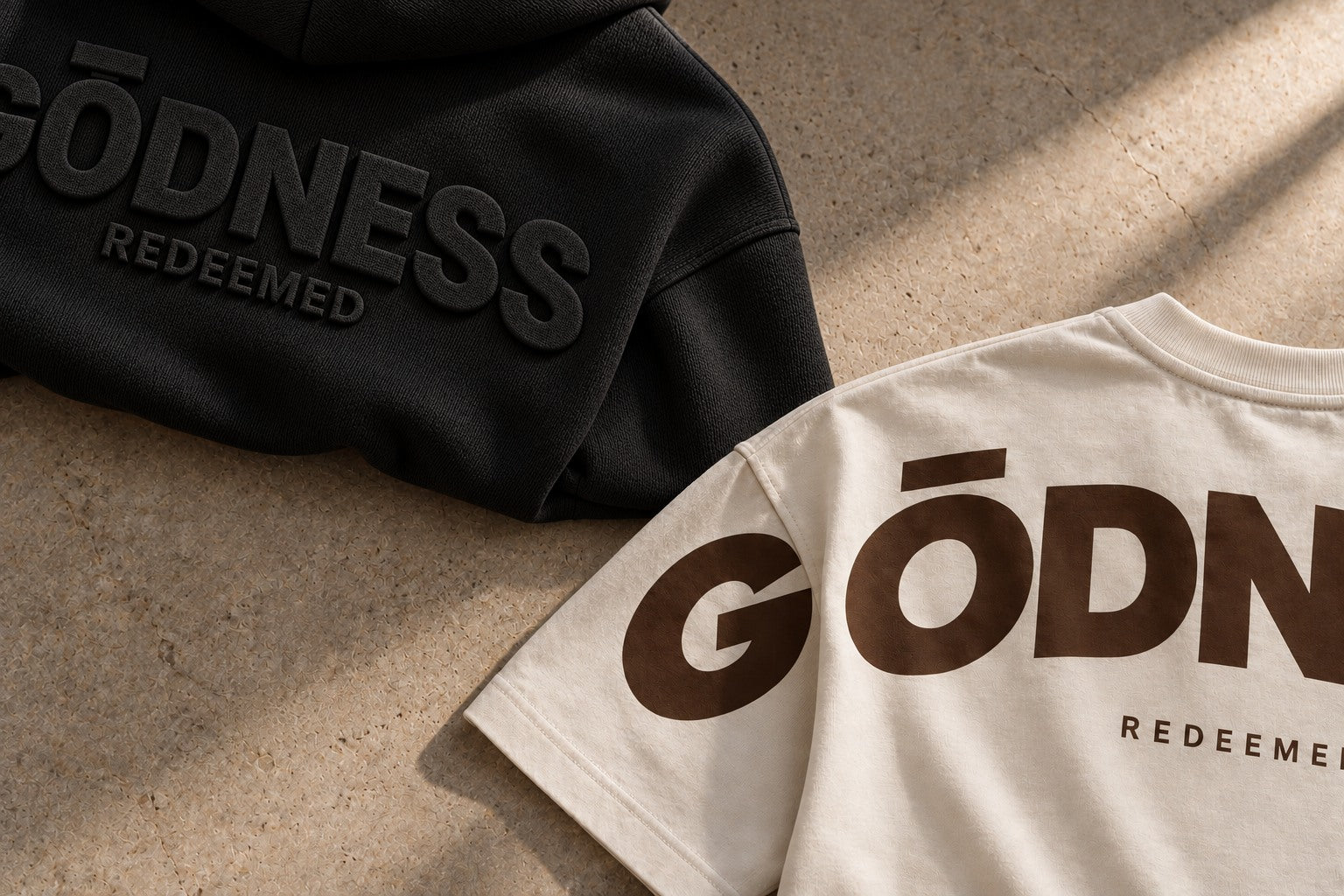 Campaign concept: partial black hoodie embossing and bone T-shirt print at opposite corners of a warm stone floor.