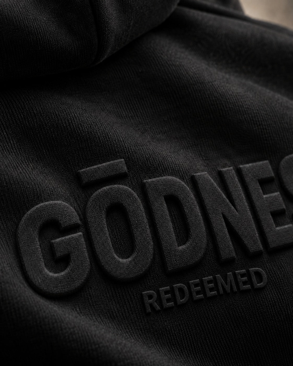 Teaser concept: close-up of a small section of sharp tonal embossing raised from black hoodie fleece.