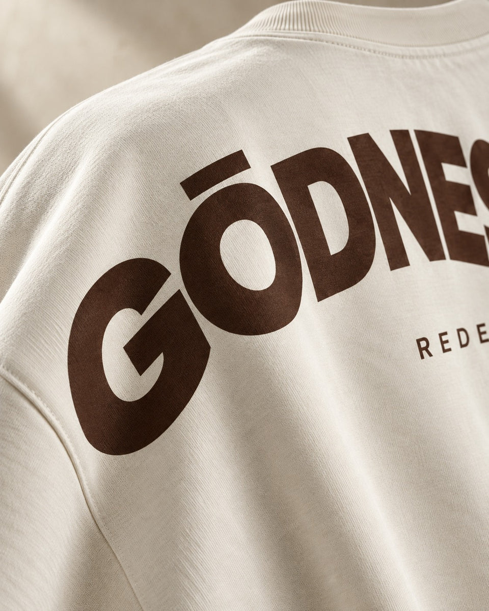 Teaser concept: an angled crop of the bone T-shirt's rear shoulder reveals part of the coffee-brown screen print.