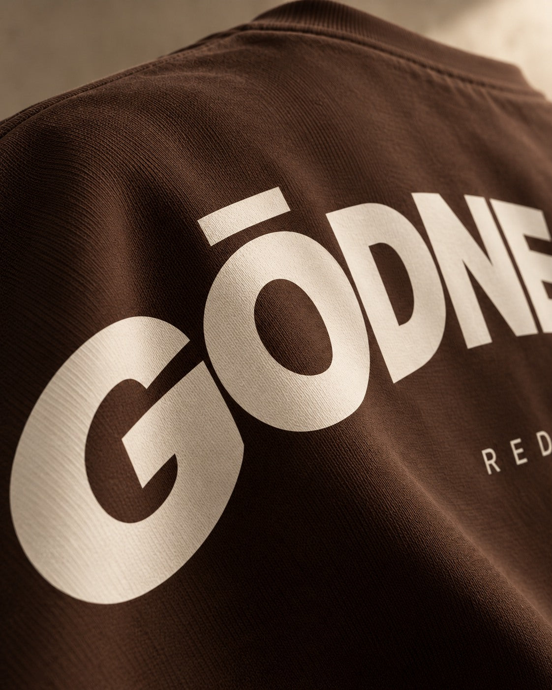 Teaser concept: an angled crop of the coffee T-shirt's rear shoulder reveals part of the bone screen print.